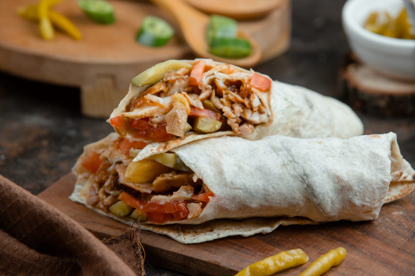 Chicken and salad wrap cut in half on a wooden board